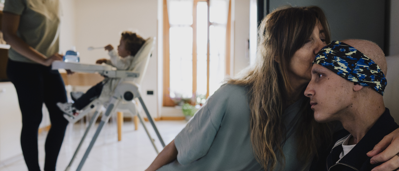 Mother smiles at her smiling son wearing a blue sweatshirt and looking at the camera